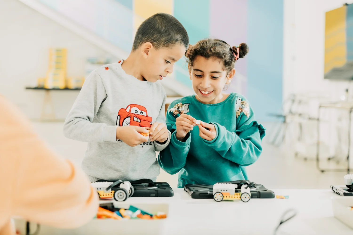 Two children building and exploring robot components together