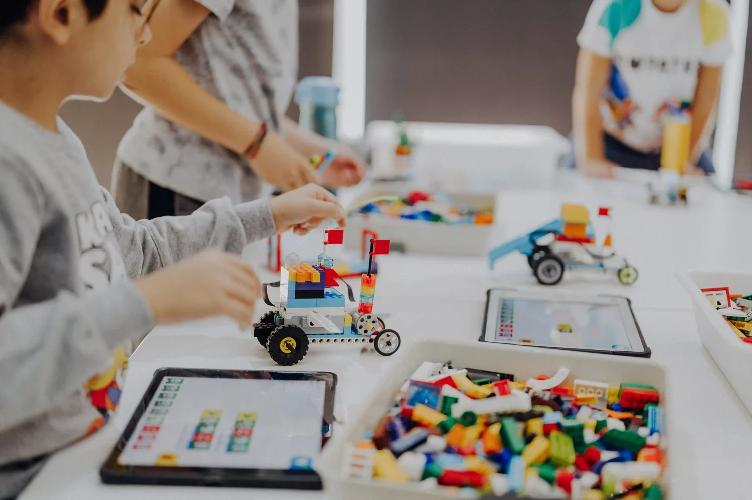 Children working with a tablet and a colourful robot model