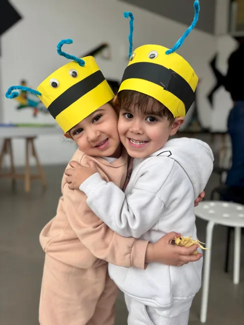 Two children wearing handmade bee hats